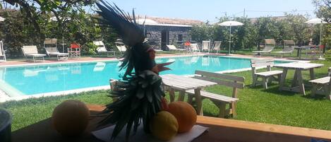 A poolside area with a table, chairs, and a tiki statue.