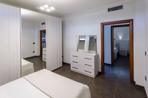 Una camera da letto con un letto, una cassettiera, uno specchio e una porta che conduce al bagno.