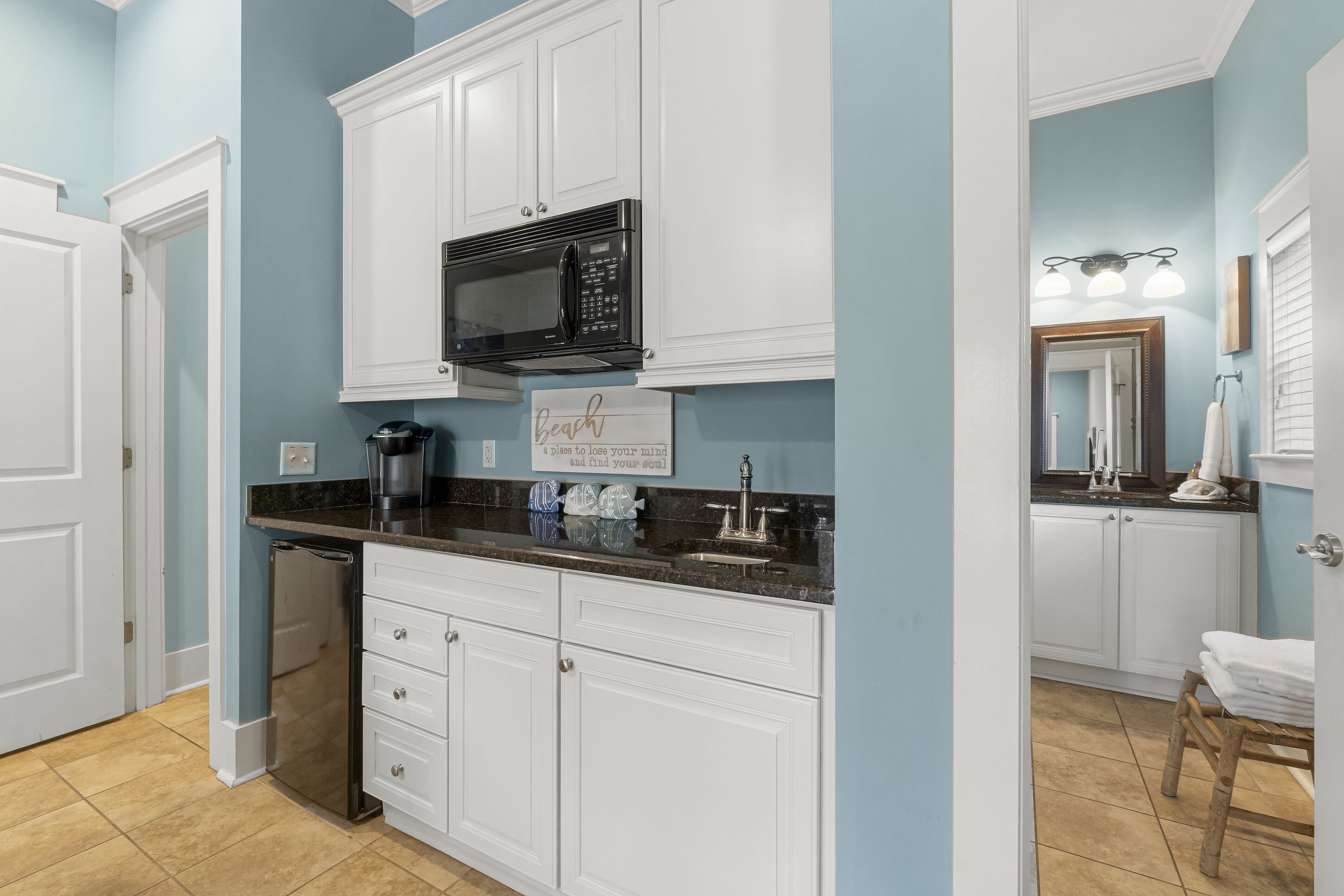 A kitchen with white cabinets, a black microwave, and a coffee maker.