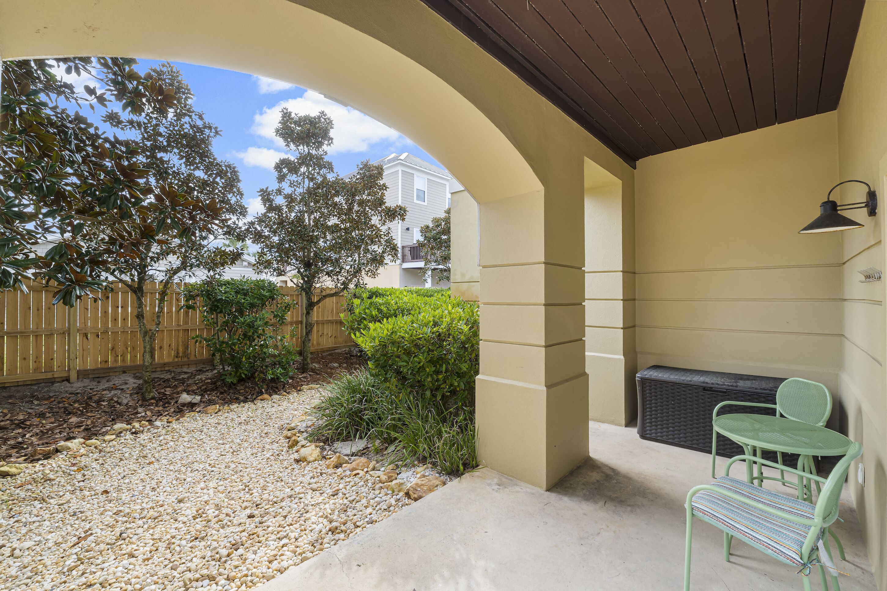 Un'area patio coperta con un angolo salotto, un riscaldatore a parete e vista su un quartiere residenziale.