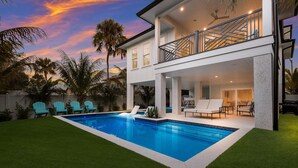 A modern two-story house with a swimming pool, outdoor seating, and a balcony. - Rooftop Deck, Private Pool and Game room! Perfect for Families! (Anna Maria)