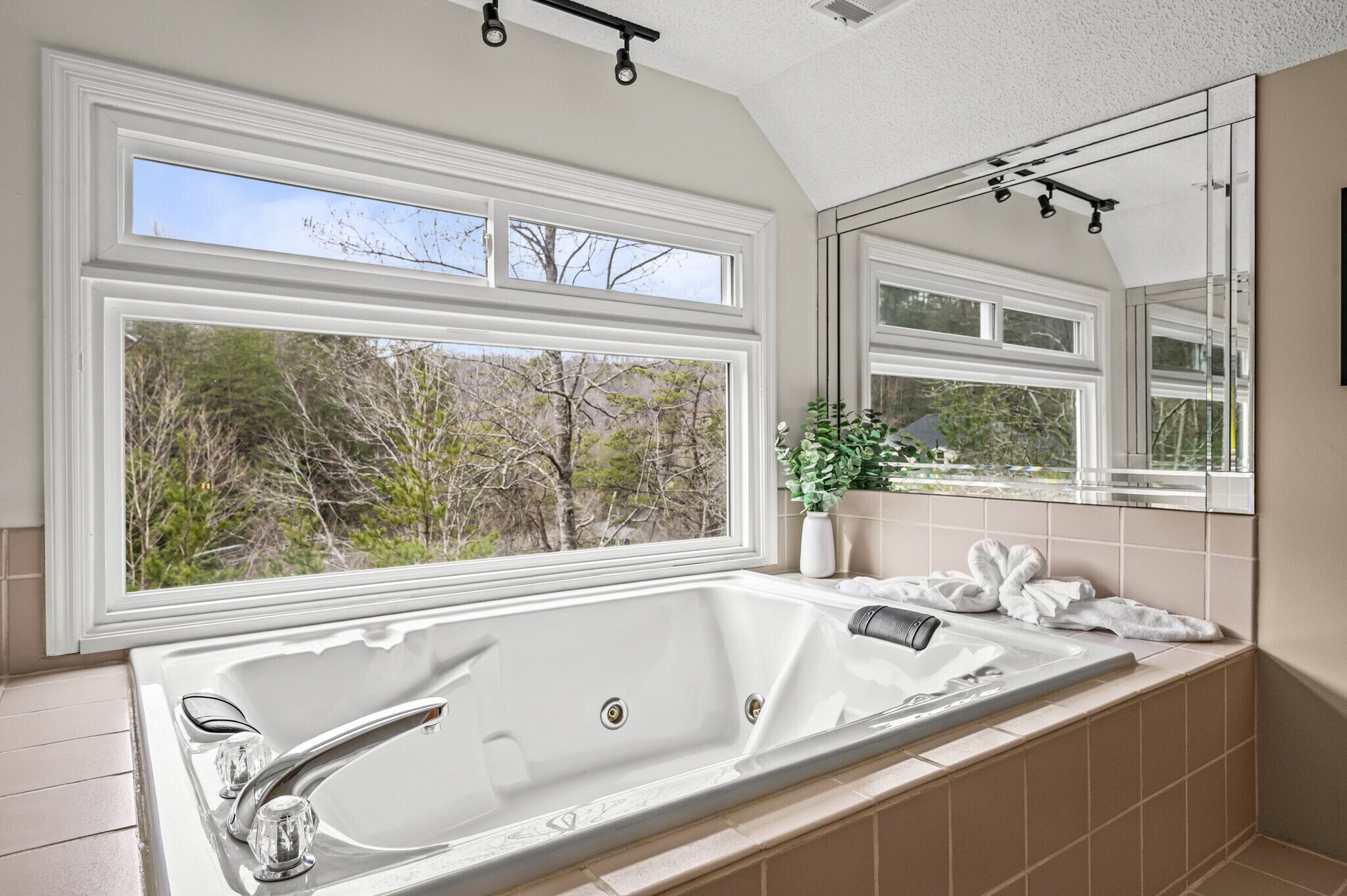 Ein Badezimmer mit großem Fenster, einer Badewanne und einem Spiegel.