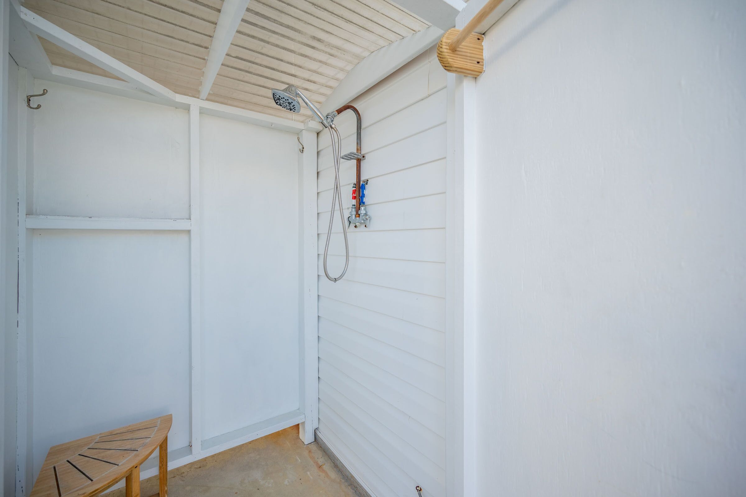 A small, enclosed space with a shower, a bench, and a wooden ceiling.