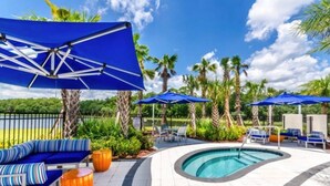 A poolside area with blue umbrellas, lounge chairs, and a swimming pool.