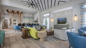 A modern living room with a dining area, featuring a large TV, comfortable seating, and a stylish ceiling design.