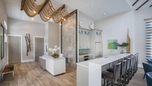 A modern kitchen with white cabinetry, a central island, and bar stools.