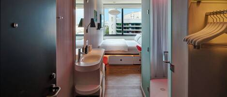 Una habitación de hotel moderna con cama central, lavamanos integrado y vestidor.