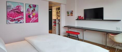 Una habitación de hotel moderna con una cama, un escritorio y un televisor.