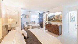 A hotel room with two beds, a wooden dresser, a large painting, and a sliding door leading to another room. - Gorgeous Beach Front Condo, Near Flagler Ave - 701 (New Smyrna Beach)