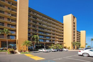 A multi-story hotel with balconies, a parking lot, and palm trees. - Mana Kai Kihei condo w/ private lanai, pool access, summer deal (Kihei)