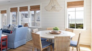 Un coin repas avec une table ronde, des chaises en osier et un lustre suspendu.