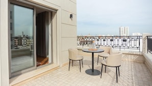 A balcony with a table and chairs, a sliding glass door, and a view of buildings in the distance. - Gray Hotel Casablanca (Casablanca)