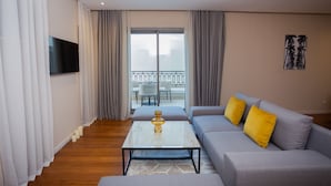 A modern living room with a grey sofa, yellow cushions, a glass coffee table, and a balcony with white chairs. - Gray Hotel Casablanca (Casablanca)