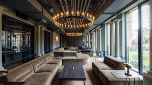 A modern lounge area with a large sectional sofa, a coffee table, and a chandelier.