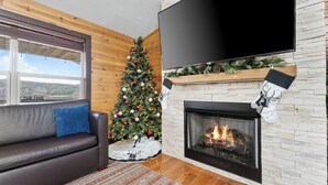 Een gezellige woonkamer met een open haard, een kerstboom, een leren bank en een grote flatscreen televisie.