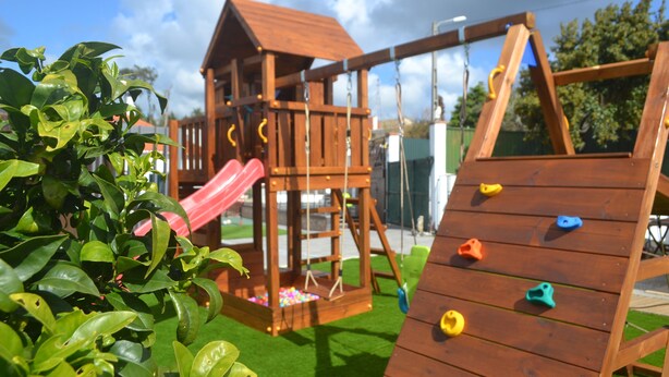 Ein hölzerner Spielplatz mit Rutsche und Kletterwand.