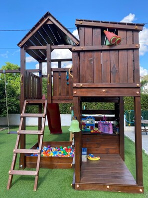 Une cabane en bois avec un toboggan, une échelle et une piscine à balles.