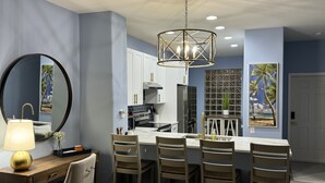 A modern kitchen with a central island, white cabinets, and a hanging light fixture.