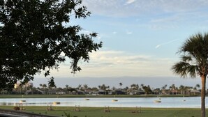 A view of a waterfront property with a wooden deck, a grassy area, and a body of water.