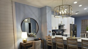 A modern kitchen with a dining area, featuring a round mirror, pendant light, and a central island with seating.