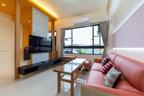 A modern living room with a sofa, a glass-top coffee table, a flat-screen TV mounted on a wall, a window with curtains, and an air conditioning unit. - yuandian (Luodong)