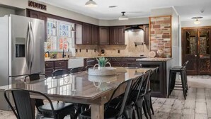 A modern kitchen with dark wood cabinets, stainless steel appliances, and a central island with chairs.