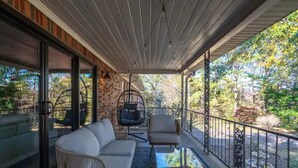 A covered balcony with a sofa, chairs, and a hanging chair.
