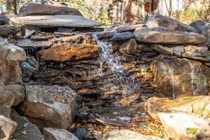 Une cascade naturelle formée par des roches, située dans une zone boisée.