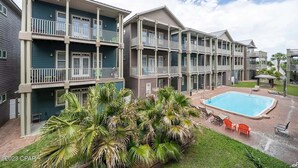 Un hôtel à plusieurs étages doté de balcons, d’une piscine et d’un aménagement paysager de style tropical.
