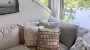 A living room with a beige sofa, patterned cushions, and a framed picture on the wall. - Lakeside in Muskoka (Huntsville)