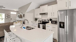 Una cocina moderna con armarios blancos, electrodomésticos de acero inoxidable y una isla curva con un fregadero.