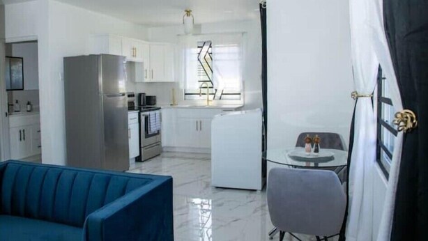 Een kleine leefruimte met kitchenette, een eethoek en een bank.