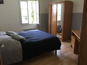 Een slaapkamer met een bed, een kledingkast en een bureau.