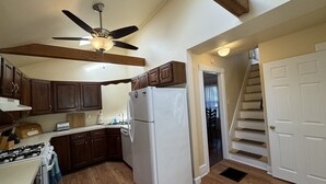 A kitchen with wooden cabinets, a white refrigerator, a gas stove, and a ceiling fan.