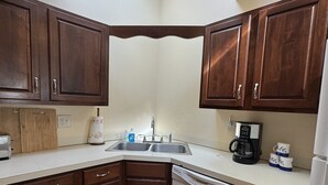 A kitchen with wooden cabinets, a dishwasher, a coffee maker, and a sink.