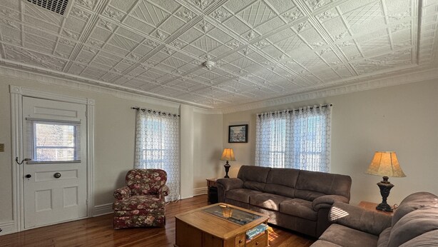 A living room with a wooden floor, a sofa, a chair, a coffee table, and a lamp.