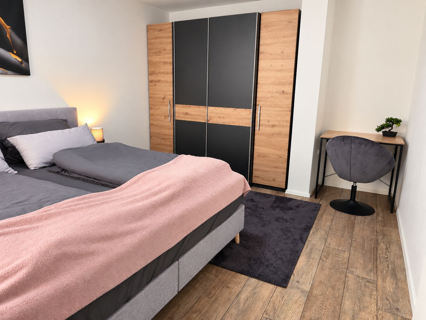 Ein Schlafzimmer mit Bett, Kleiderschrank, Schreibtisch und Stuhl.