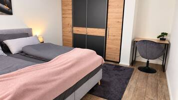 Ein Schlafzimmer mit Bett, Kleiderschrank, Schreibtisch und Stuhl.