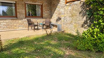 A patio with wicker furniture and a stone wall.