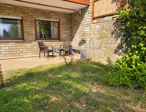 Un patio con mobiliario de mimbre y un muro de piedra.