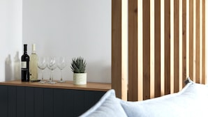 Une table en bois avec des bouteilles de vin et des verres, une plante en pot et un meuble noir.