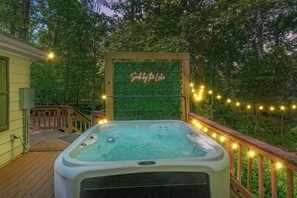 Ein Whirlpool auf einer Holzterrasse, mit einem neonbeschrifteten Schild 'Soda by the Lake' und Lichterketten.