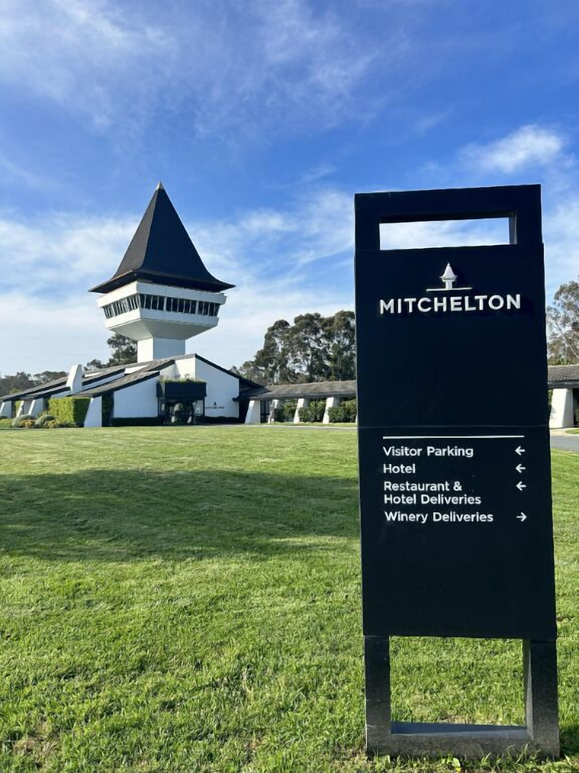 Ein Schild mit der Aufschrift 'MITCHELTON' und Richtungspfeilen zu 'Besucherparkplatz', 'Hotel', 'Restaurant- und Hotellieferungen' sowie 'Weinerielieferungen'.