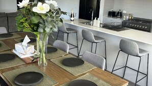Uma sala de jantar moderna com uma mesa de madeira, cadeiras cinzas e um vaso com flores.
