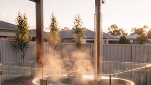 Uma sauna de madeira com chaminé, um banco e uma mesa pequena com velas.