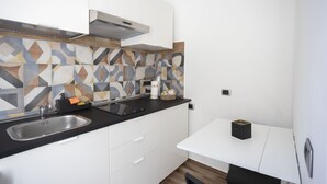 Eine moderne Küche mit schwarzer Arbeitsplatte, weißen Schränken und einer gemusterten Spritzschutzwand.