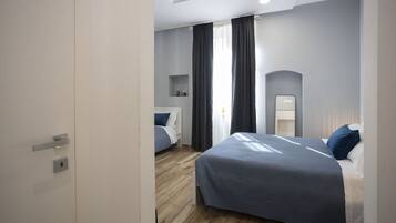 Una moderna camera d'albergo con un letto grande, un letto più piccolo e una scrivania.