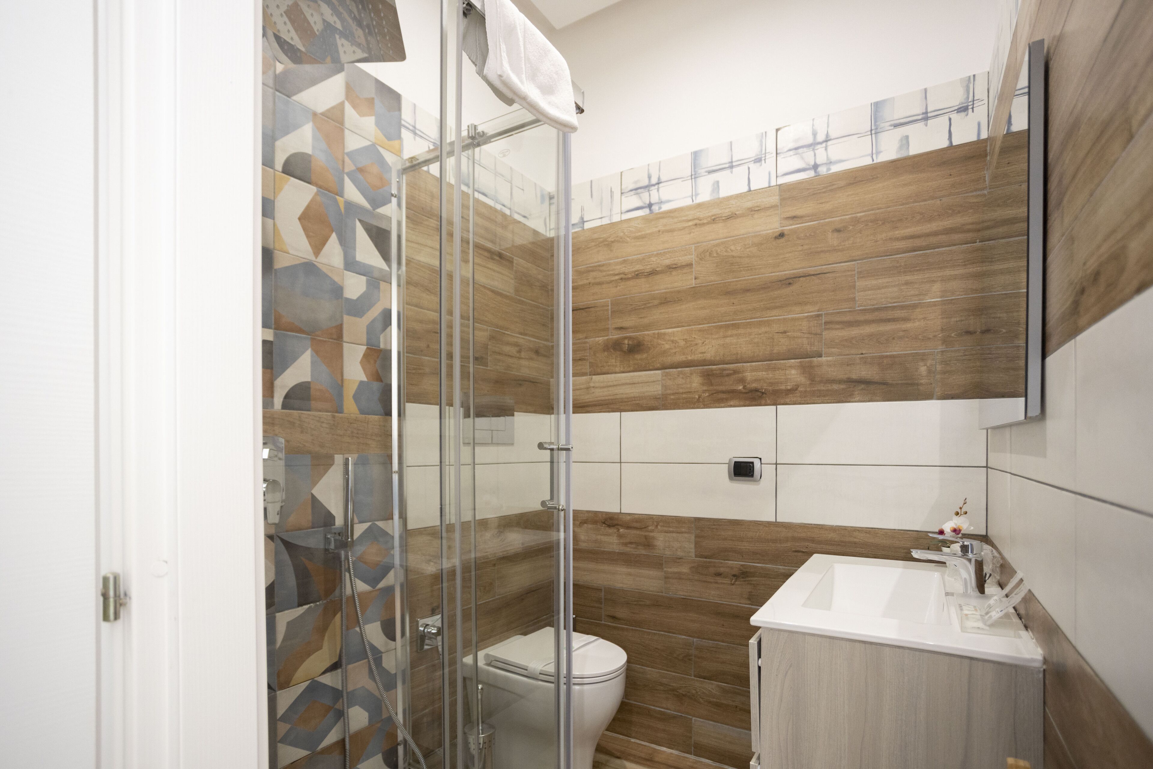 Un baño moderno con cabina de ducha de vidrio, inodoro y lavabo con tocador de madera.