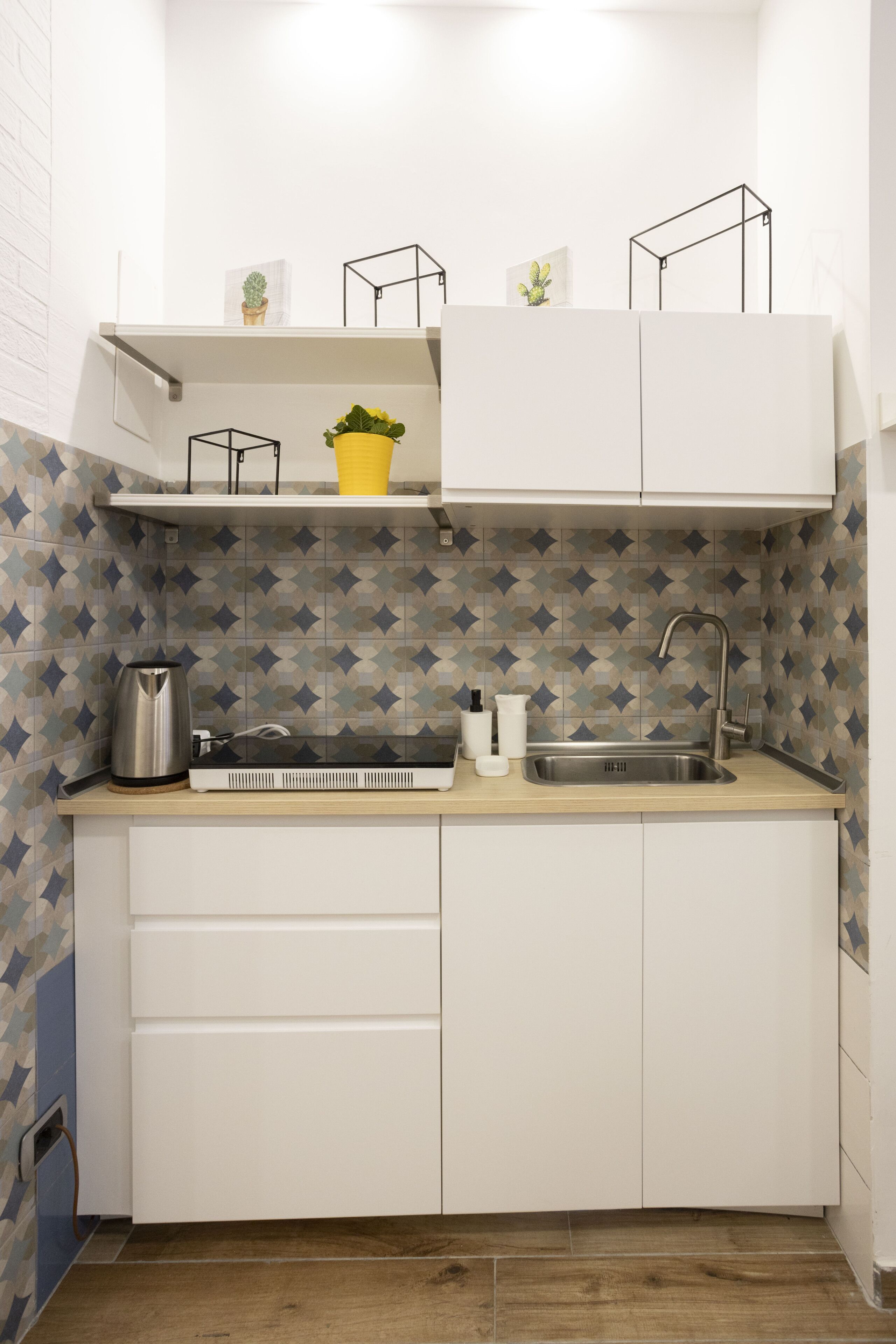 A compact kitchen with a sink, a kettle, and a small countertop.