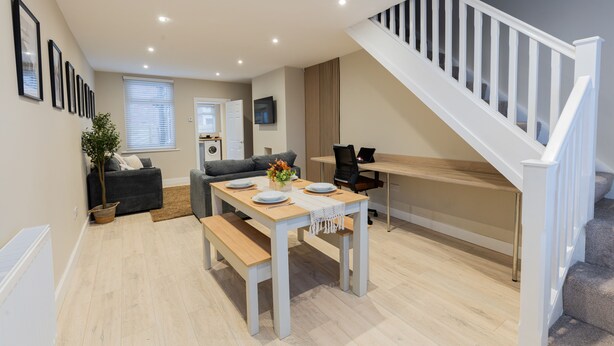 Un espacio de estar moderno con comedor, una escalera y una zona de estar.
